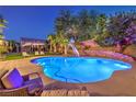 Inviting backyard pool with slide, lounge chairs, and lush landscaping for relaxation and recreation at 4737 Barcelona Ridge Ct, Las Vegas, NV 89129