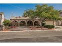 Charming single-story home featuring arched entryways, a well-manicured yard, mature shade tree, and attached two-car garage at 6513 Hyde Ave, Las Vegas, NV 89107