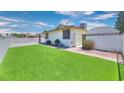 An attractive backyard with green grass, a privacy fence, and a view of blue skies and fluffy clouds at 706 Red Lake Way, Las Vegas, NV 89110