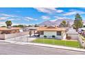 A charming exterior view of a single-story home with a carport, fenced yard, and mountain views at 706 Red Lake Way, Las Vegas, NV 89110
