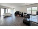 Modern living room with a white sofa, large windows, and wood-look tile flooring at 10879 Artesano Ave, Las Vegas, NV 89135