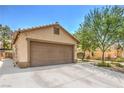 Spacious two-car garage with a wide driveway, desert landscaping, and tile roof at 5453 Palisades Quad Ave, Las Vegas, NV 89122