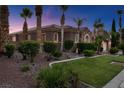 Beautiful home with desert landscaping, green lawn, mature palm trees and a tiled roof at 8209 Chapelle Ct, Las Vegas, NV 89131
