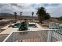 Backyard view of a sparkling blue pool with a sunning deck and several palm trees, set against a desert backdrop at 156 N Parawan St, Henderson, NV 89015