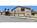 Low-angle view of a condominium building with garages, balconies, and palm trees under a clear blue sky at 2000 Gravel Hill St # 203, Las Vegas, NV 89117