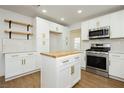 Open-concept kitchen with stainless steel oven and microwave, butcher block island, and modern white cabinets at 2107 Fountain Springs Dr, Henderson, NV 89074