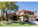 Two-story home with an attached three-car garage, a well-kept lawn, and mature trees at 2208 Fiero Dr, Las Vegas, NV 89134