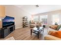 Bright living room features wood floors, a comfortable seating arrangement, and natural light through large windows at 4909 Desert Poppy Dr, Las Vegas, NV 89130