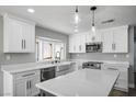 Bright kitchen features white cabinets, quartz counters, stainless appliances, and a farmhouse sink under a window at 7060 W Rome Blvd, Las Vegas, NV 89131