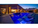 Gorgeous backyard pool with illuminated water features, in-pool loungers, and views of the home at 11248 Rebel Dome Ct, Las Vegas, NV 89141