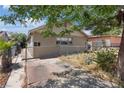 View of a single-story house with chain link fencing and a paved driveway, some landscaping, and a large tree providing shade at 2528 Sunrise Ave, Las Vegas, NV 89101