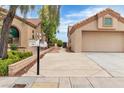 View of home's front exterior featuring a 2 car garage, mature landscaping, and a spacious front yard at 2532 Big Timber Dr, Las Vegas, NV 89134