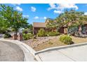 Beautiful front yard with well-maintained landscaping, including mature trees, shrubs, and decorative rock features at 3930 Maranatha Cir, Las Vegas, NV 89103