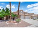 Charming two-story home with a well-manicured lawn, palm trees, and a three car garage at 9500 Catalina Cove Cir, Las Vegas, NV 89147
