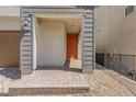 Covered entryway with brick-paved walkway leads to an orange front door with house number at 10776 Maltese Falcon Ave, Las Vegas, NV 89129