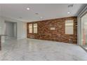 Open-concept living space features wood-look accent wall, marble floors, and sliding door at 11377 Gravitation Dr, Las Vegas, NV 89135