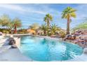 A luxurious backyard pool with a rock waterfall feature surrounded by desert landscaping at 1239 N Hollywood Blvd, Las Vegas, NV 89110