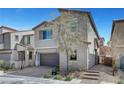 View of a two-story home with gray exterior paint, a two-car garage and desert landscaping in the front at 15 Santo Mio Ct, Henderson, NV 89011