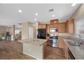 Well-equipped kitchen with granite countertops, wooden cabinets, black appliances, and an island at 7028 Weavers Pl, North Las Vegas, NV 89084