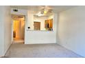 A well-lit living room featuring neutral-toned walls, carpet, and an open view of the kitchen at 7163 S Durango Dr # 113, Las Vegas, NV 89113