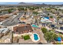 An aerial view showcases the homes backyard pool and landscaping with mountain views at 1004 Woodside Ct, Henderson, NV 89015