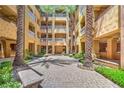Picturesque courtyard showcasing tall palm trees and brick pavers to add architectural elegance at 15 Via Mantova # 302, Henderson, NV 89011