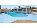 Backyard view of the in-ground pool, surrounded by concrete, a white fence, and desert landscaping at 667 Del Prado Dr, Boulder City, NV 89005