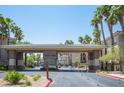 Community entrance with covered gate and lush palm trees lining the entrance at 7155 S Durango Dr # 205, Las Vegas, NV 89113