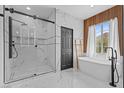 Modern bathroom featuring a sleek glass-enclosed shower and elegant soaking tub near a bright window at 10300 S Dapple Gray Rd, Las Vegas, NV 89178