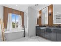 Modern bathroom with dual vanity, soaking tub, wood accent wall, and marble tile at 10300 S Dapple Gray Rd, Las Vegas, NV 89178