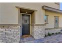 Inviting front entrance with a dark-colored door, stone accents, brick steps and a 'hello' doormat at 10360 Pescado Ln, Las Vegas, NV 89135