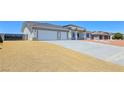 A single-story home featuring desert landscaping, a large driveway, and a modern architectural design at 2150 S Manzanita Dr, Pahrump, NV 89048