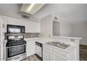 Galley kitchen featuring stainless appliances, tile backsplash, and bright white countertops at 3060 Tarpon Dr # 102, Las Vegas, NV 89120