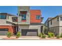 A modern home with a gray stucco and red siding exterior, and well-manicured landscaping at 3194 Lumassina Way, Henderson, NV 89044