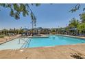 Community pool with lounge chairs, umbrellas, and a shallow wading area with handicap-accessible railings at 3194 Lumassina Way, Henderson, NV 89044