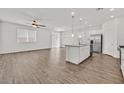 Bright, open-concept living space with wood flooring, a ceiling fan, and an eat-in kitchen with stainless steel appliances at 8011 Cavazzo Ave, Las Vegas, NV 89178