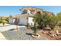 Two story home featuring a two car garage and desert landscaping with trees and rock accents at 9105 Chenin Ave, Las Vegas, NV 89129