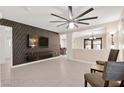 Open-concept living room features stylish accent wall and a view into the dining area with modern ceiling fan at 11755 Garland Grove Ln, Las Vegas, NV 89183