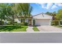 Charming single-story home with lush green lawn, mature trees, and a brick driveway to a two-car garage at 11775 Woodbrook Ct, Las Vegas, NV 89141