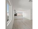 Open-concept living room and kitchen featuring light wood flooring, white walls, and natural light at 2618 Lily Point St, Las Vegas, NV 89156
