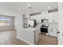 Well-lit kitchen featuring white cabinets, stainless steel appliances, a marble countertop island, and wood-look flooring at 4433 Pioche Ave, North Las Vegas, NV 89032
