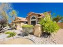 Exterior view of a home with desert landscaping, rocks, mature shrubs, and a warm color palette at 4620 N Tee Pee Ln, Las Vegas, NV 89129