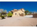 Exterior side view of a desert home with a spacious parking area and neutral color scheme at 4620 N Tee Pee Ln, Las Vegas, NV 89129
