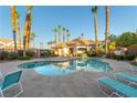 Community pool with a jacuzzi surrounded by lush landscaping, seating, and a building with a red tile roof at 5855 Valley Dr # 2145, North Las Vegas, NV 89031