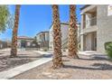 Community pool area with wrought iron fence, tile roofed buildings, and palm trees at 6160 Rumrill St # 215, Las Vegas, NV 89113