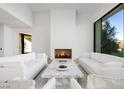 Elegant living room featuring a modern fireplace, white sofas, marble coffee table, and a view of the outdoors at 68 Sun Glow Ln, Las Vegas, NV 89135