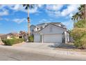 Charming two-story home featuring a two-car garage, desert landscaping, and mature palm trees at 6909 Fruit Flower Ave, Las Vegas, NV 89130