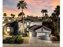 Charming two-story home featuring a two-car garage, desert landscaping, and mature palm trees during sunset at 6909 Fruit Flower Ave, Las Vegas, NV 89130