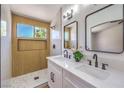 Bathroom with double sink vanity, updated lighting and mirrors, and a glass enclosed shower with niche at 410 Aloha Dr, Henderson, NV 89015