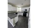 Charming kitchen with white cabinets, black appliances, granite countertops, and tiled floors at 5709 Nobleton Ct, North Las Vegas, NV 89081